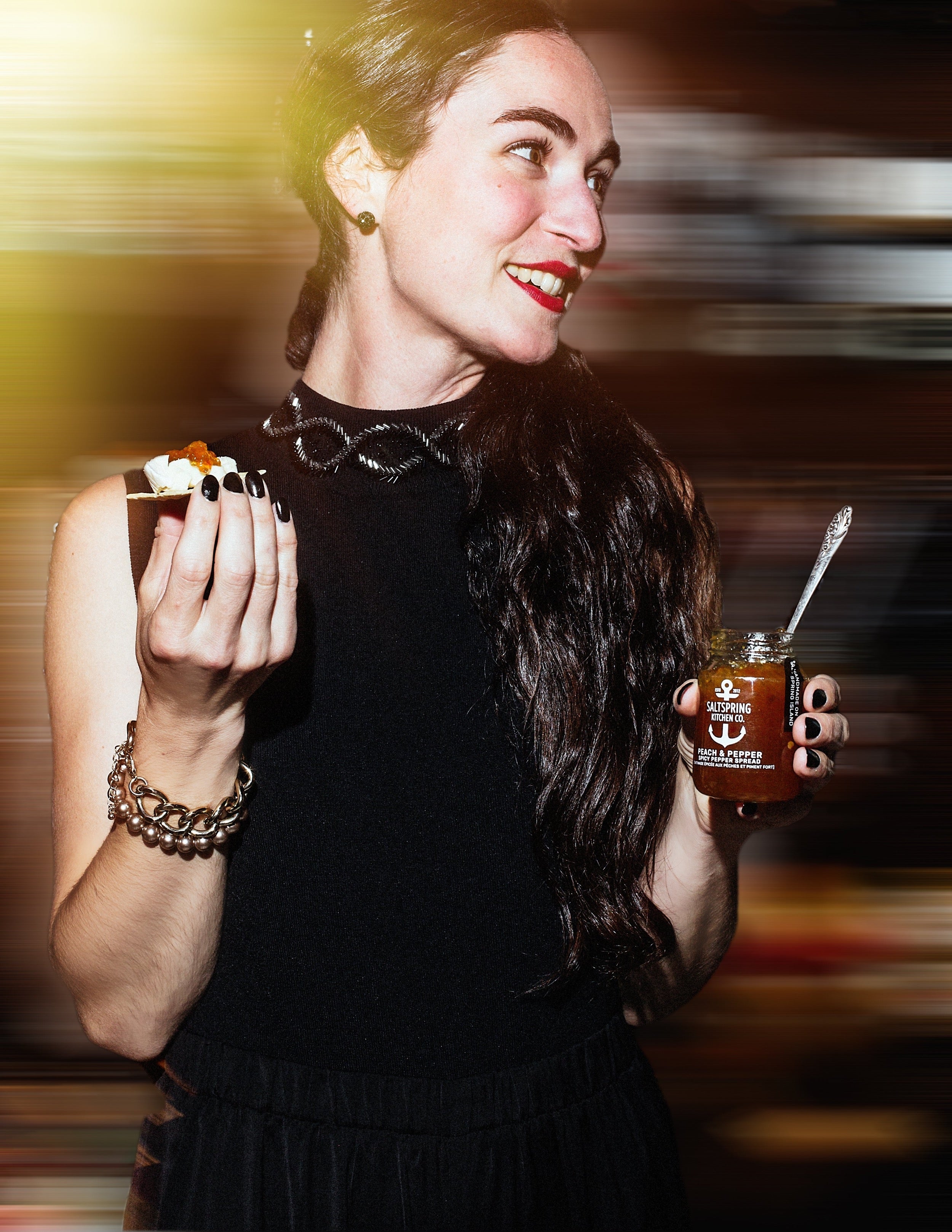 Salt Spring Kitchen Company Peach and Pepper Spicy Pepper Spread on a cracker with woman holding a jar