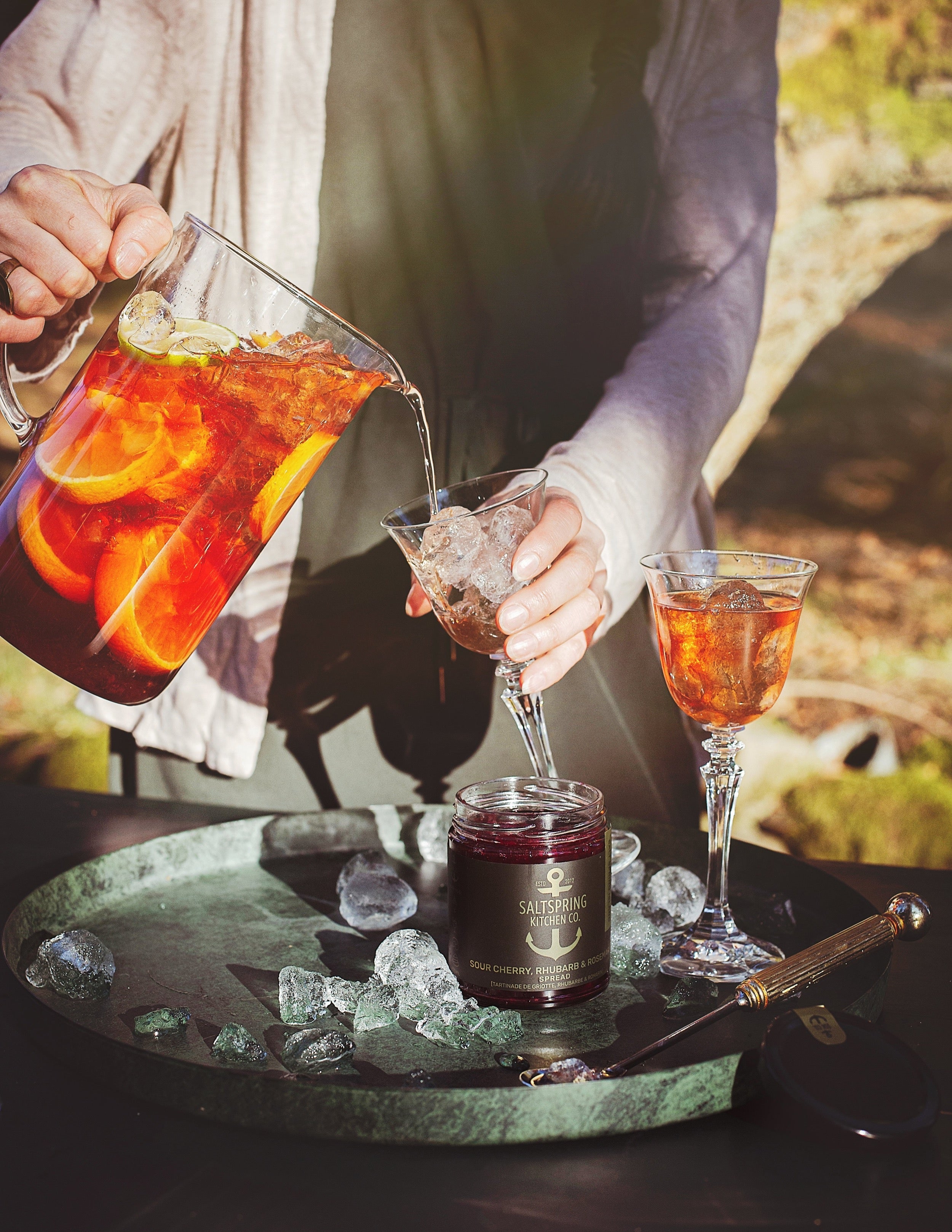 Salt Spring Kitchen Company Sour Cherry, Rhubarb and Rosemary Spread with pitcher of drinks and summer scene